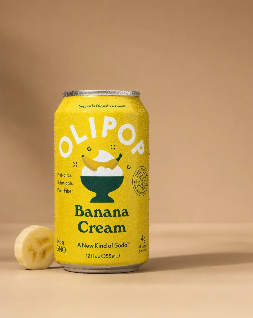 The OLIPOP can on a clay toned surface beside a halved banana, soft window light