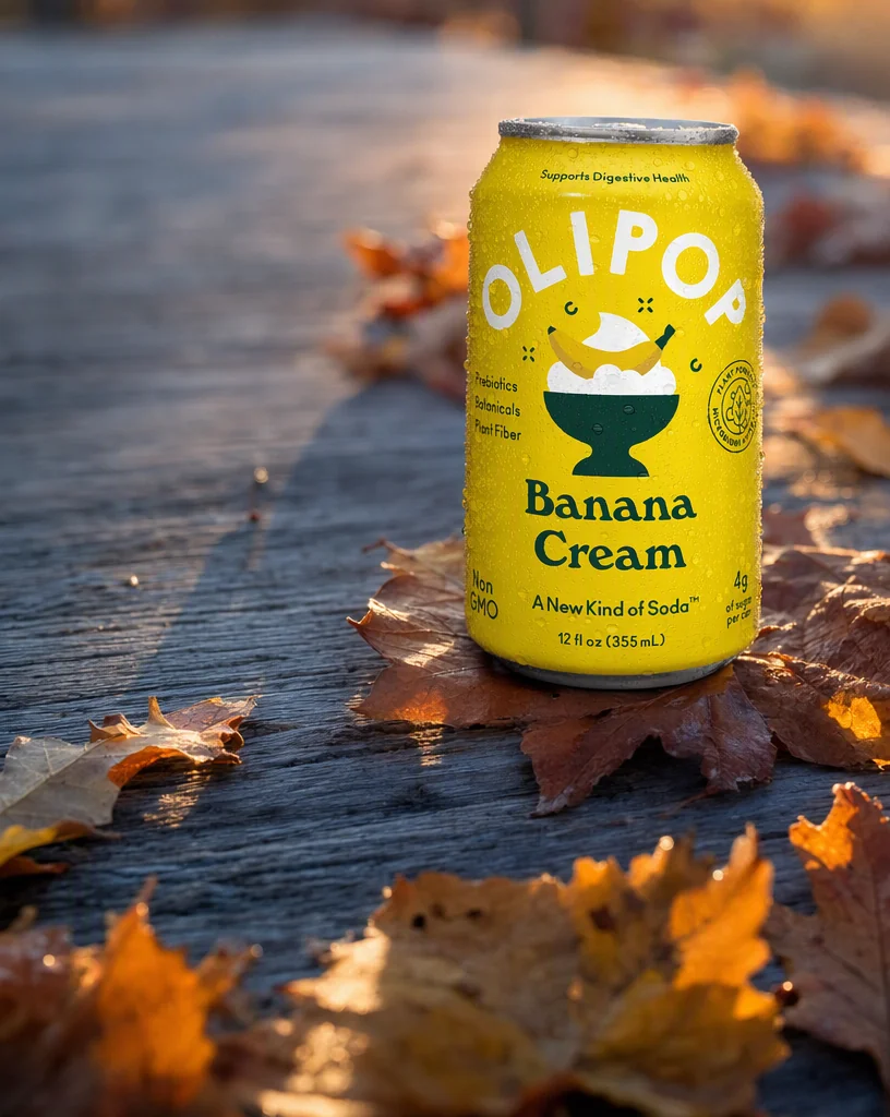The OLIPOP can on silvered timber among rust and ochre autumn leaves in low sun