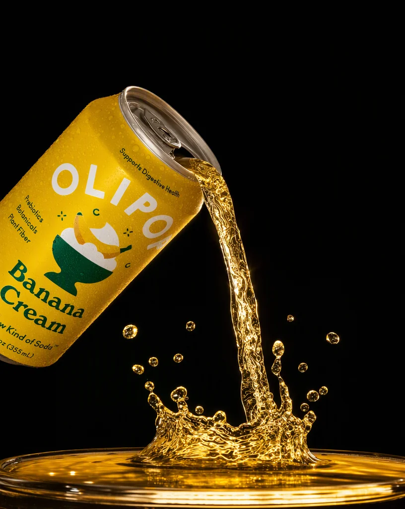 Soda pouring from the OLIPOP can into a shallow dish, splash crowning, backlit on black
