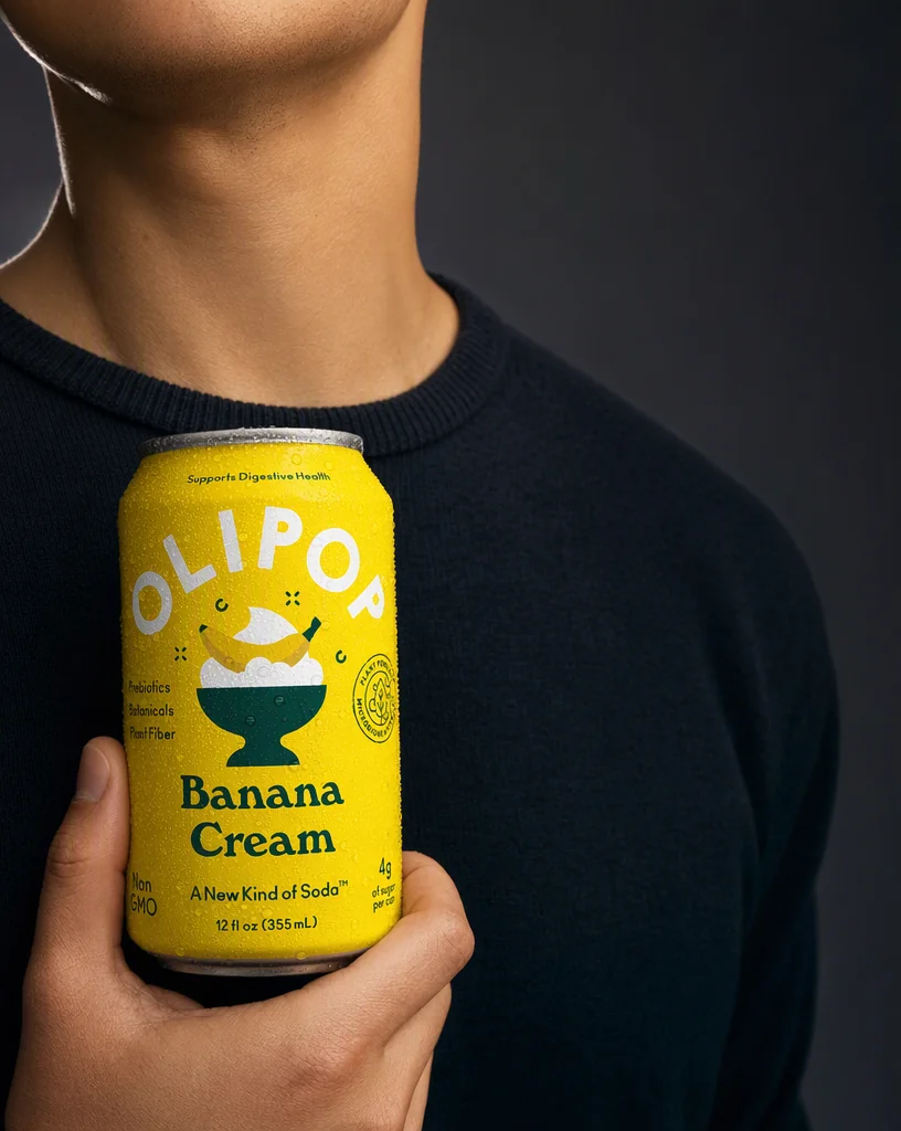 A person in a navy knit, cropped at the chin, holding the OLIPOP can at the chest